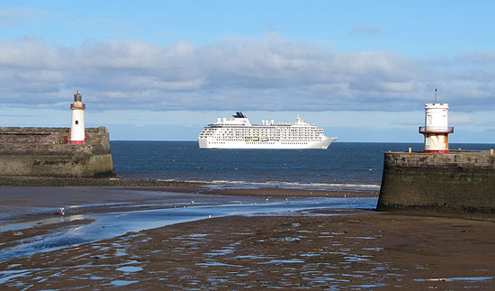The World liner beyond Whitehaven harbour at low tide
