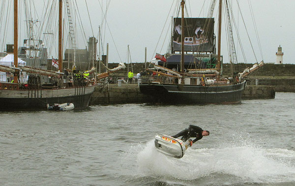 Jet Ski leaps into the air in front of tall ships