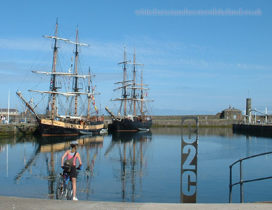 A cyclist at the start of the C2C route with tall ships